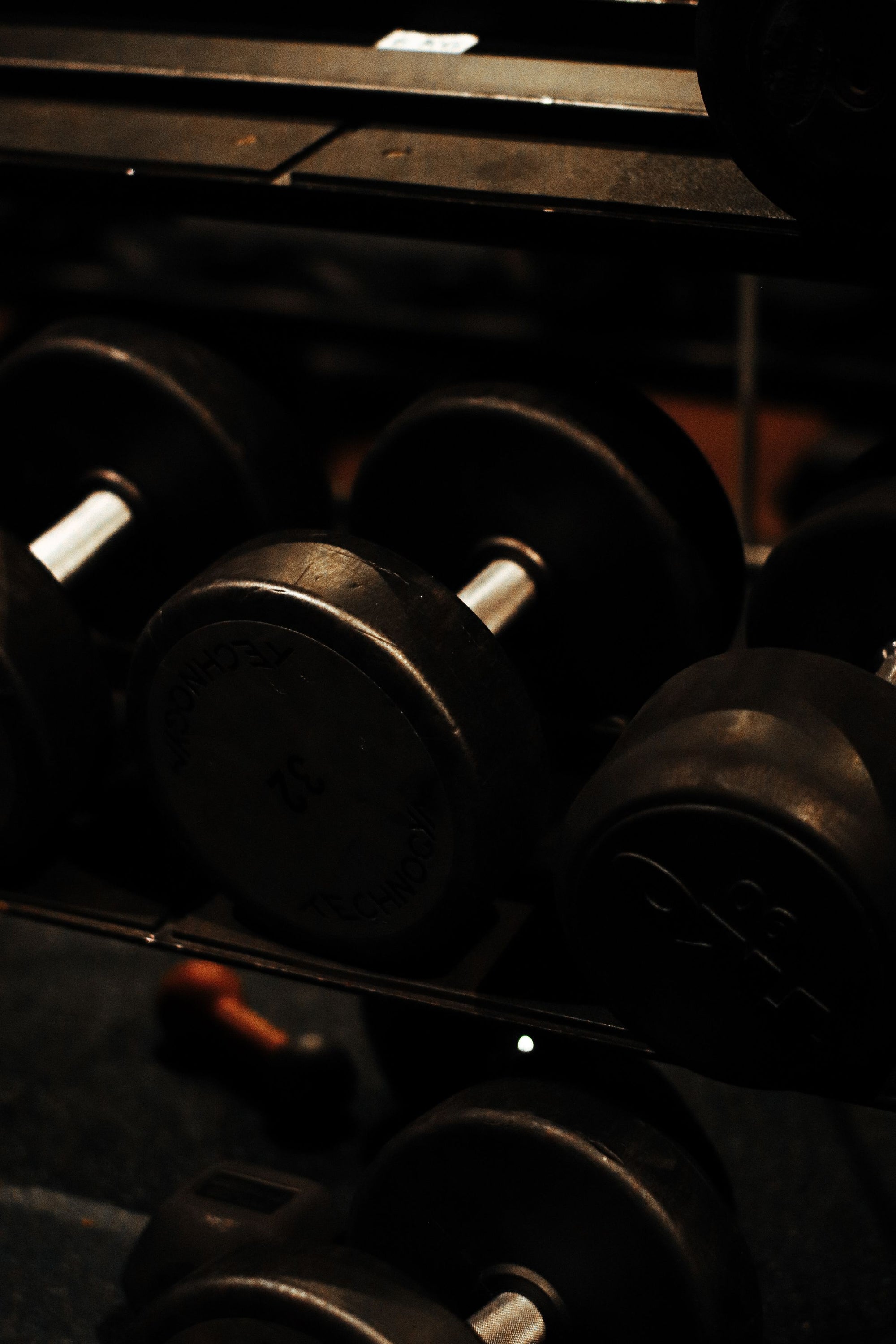 Dark, out-of-focus rack of dumbbells in low light