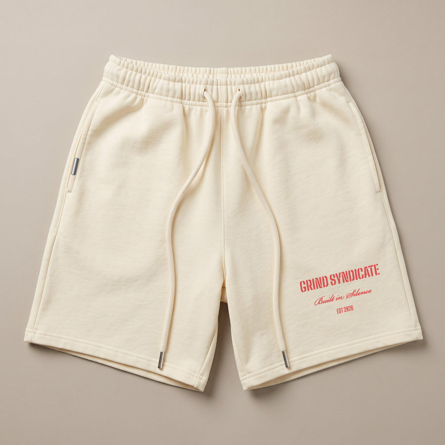 Origin Shorts in Ivory, laid flat, with the Grind Syndicate lockup on the leg in red